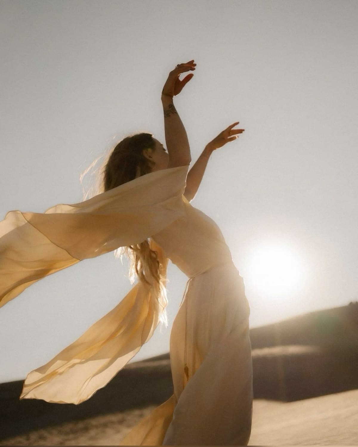 A woman in flowing fabric moving freely in warm golden light