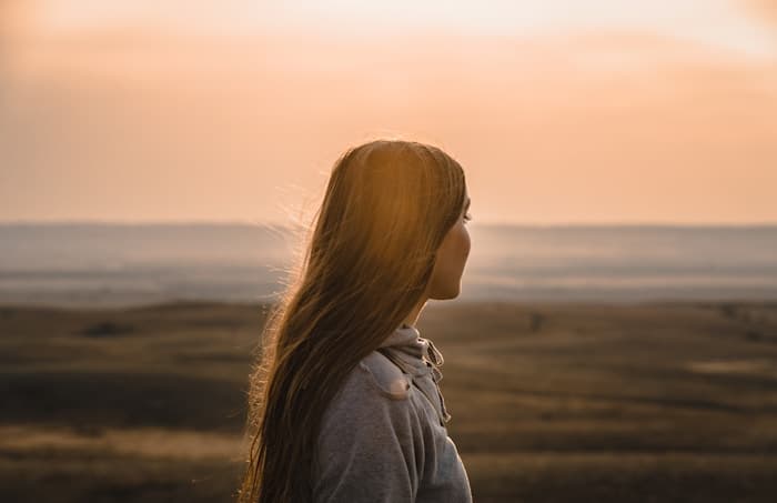 A woman at golden hour looking toward the horizon